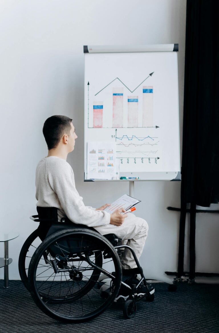 Man in wheelchair presenting data on a graph during a business meeting.